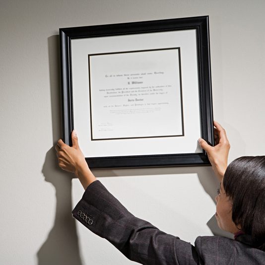 Business woman hanging framed certificate