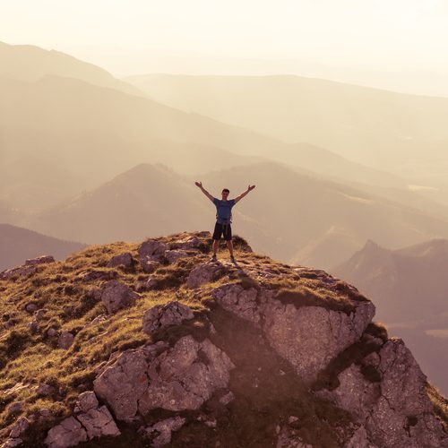 silhouette of successful man on the top of mountain. Concept of sport motivation inspiration